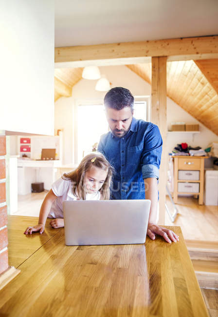 Padre e hija usando portátil en casa - foto de stock