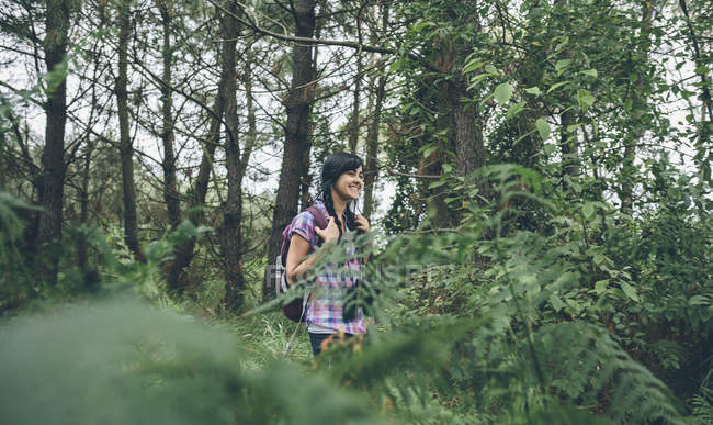 Giovane donna sorridente con zaino che cammina nella foresta — Foto stock