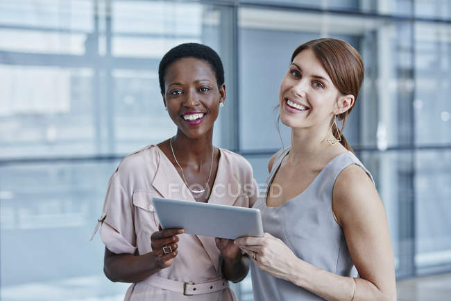 Dos empresarias con tablet digital en oficina moderna - foto de stock