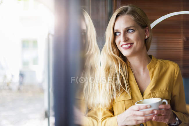 Mujer sonriente en una cafetería - foto de stock