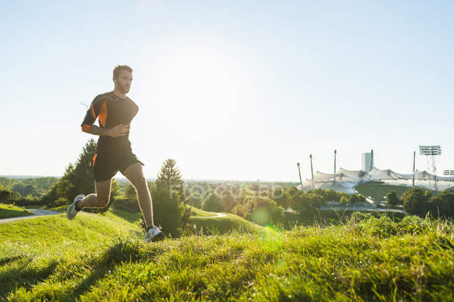 Hombre deportivo corriendo en el prado en el parque - foto de stock