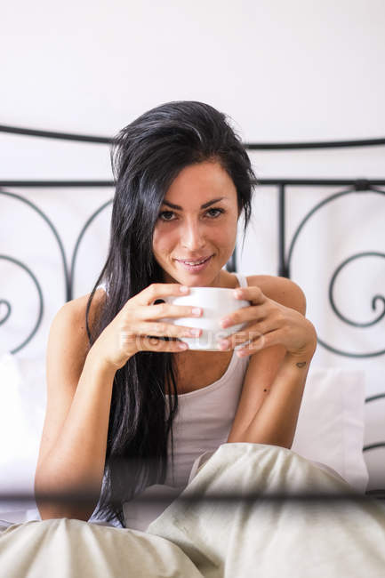 Woman drinking coffee in bed — Stock Photo