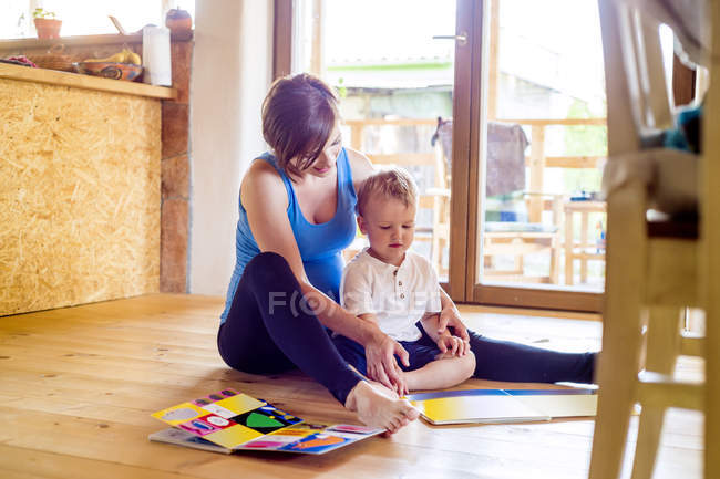 Вагітна мати, дивлячись на картину книги з її маленький син — стокове фото