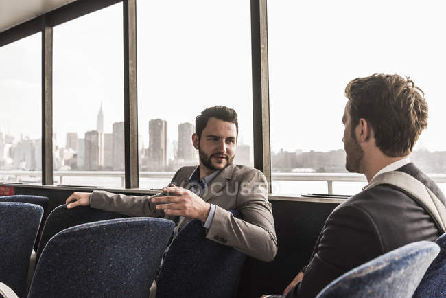 Due uomini d'affari che parlano sul ponte passeggeri di un traghetto — Foto stock