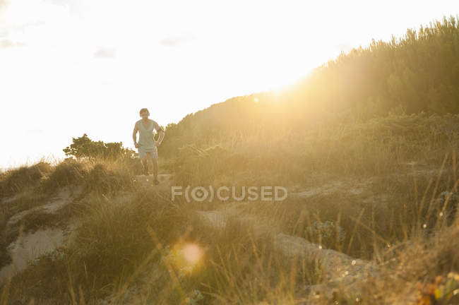 Junger Mann joggt bei Sonnenaufgang in Düne — Stockfoto