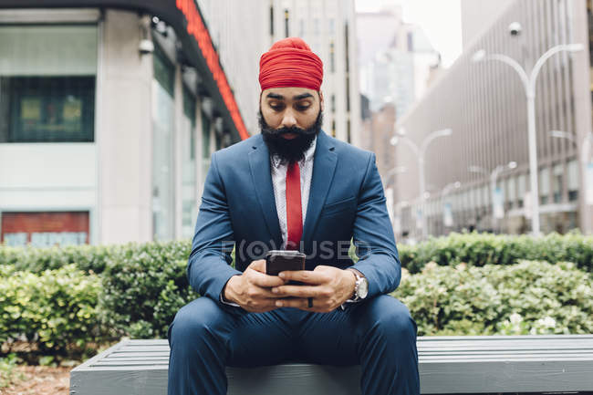 Indischer Geschäftsmann sitzt auf Bank und benutzt Smartphone in manhattan, ny, usa — Stockfoto