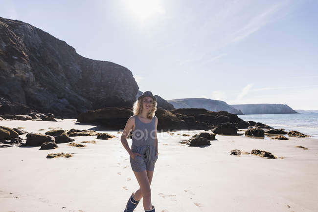Блондинка дівчина-підліток в капелюсі, що йде на пляжі — стокове фото