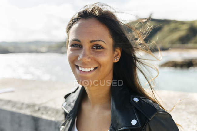 Portrait of happy young woman with brown hair standing in nature — Stock Photo