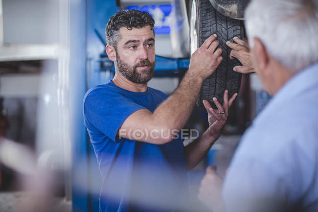Mécanicien automobile en atelier avec client masculin — Photo de stock
