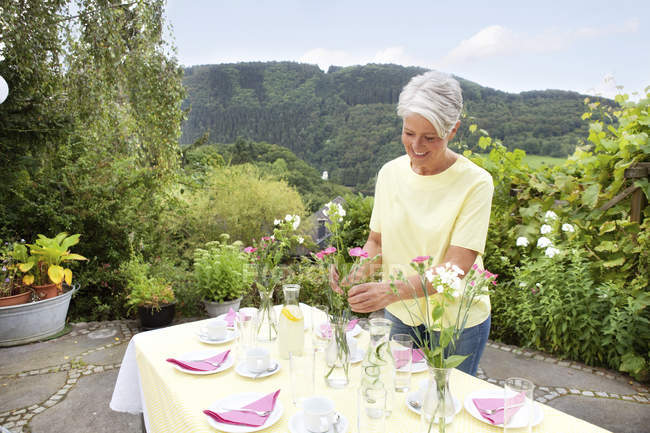 Femme mature décoration table de jardin pour fête d'anniversaire — Photo de stock