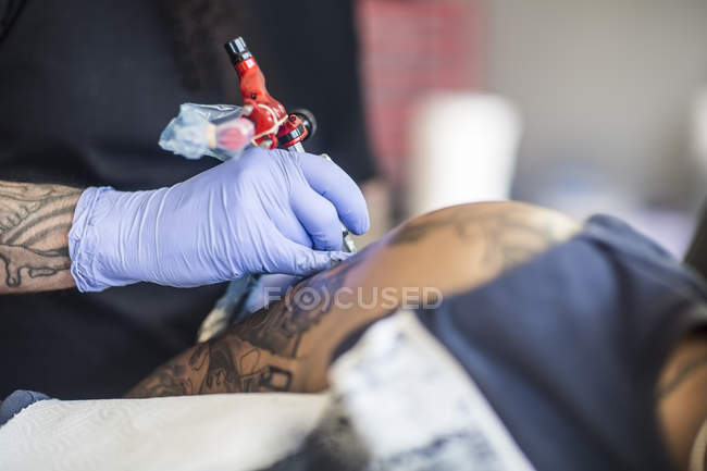 Татуировщик татуирует руку — стоковое фото