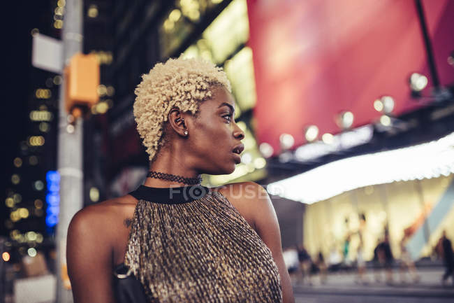 Giovane donna sorridente che cammina su Times Square di notte, New York, USA — Foto stock