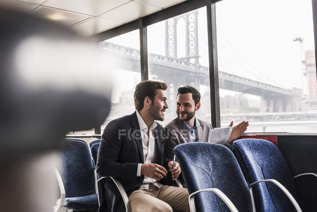 Due uomini d'affari con documento che parlano sul ponte passeggeri di un traghetto — Foto stock