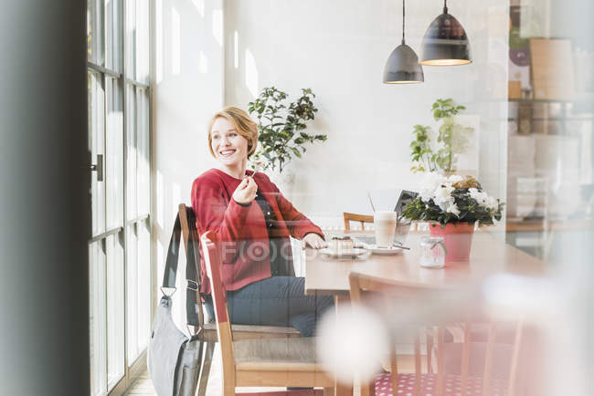 Smiling young woman sitting in a cafe — Stock Photo
