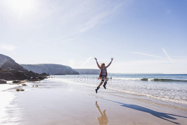 Adolescente pulando de alegria na praia de areia — Fotografia de Stock