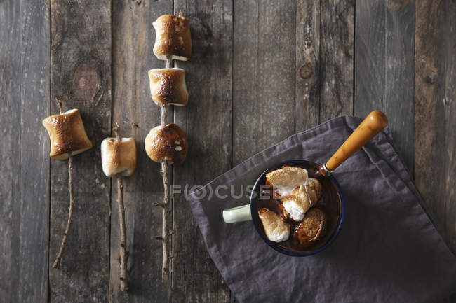 Hot chocolate with fire-roasted marshmallows on wooden table, top view — Stock Photo
