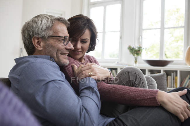 Smiling mature couple sitting on sofa at home — Stock Photo