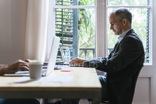 Бізнесмен, сидячи за столом і працюють на ноутбук — стокове фото