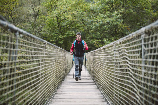 Escursionista uomo a piedi sul ponte nella natura — Foto stock