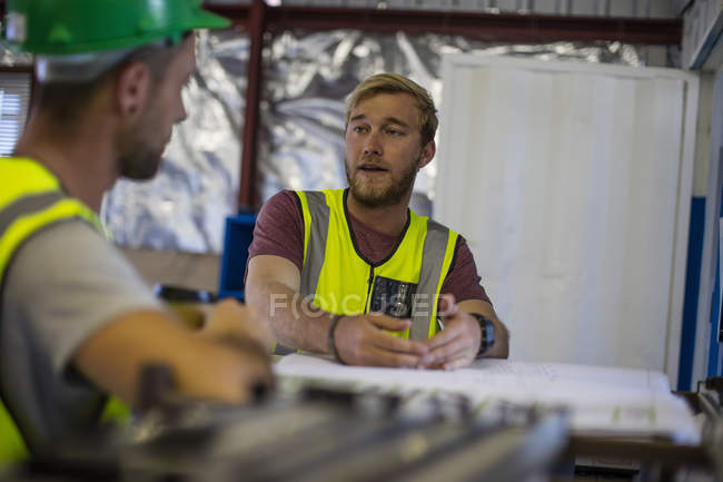 Строитель и инженер обсуждают проект в офисе на стройплощадке — стоковое фото
