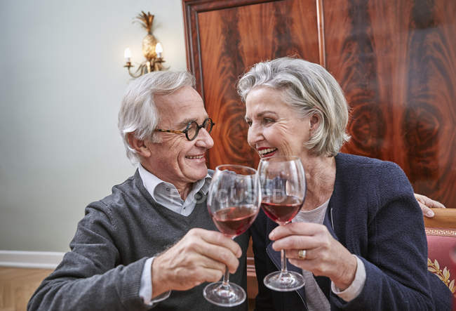 Smiling senior couple clinking red wine glasses — Stock Photo