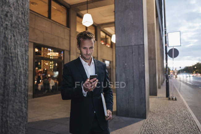 Businessman looking at smartphone in the evening — Stock Photo