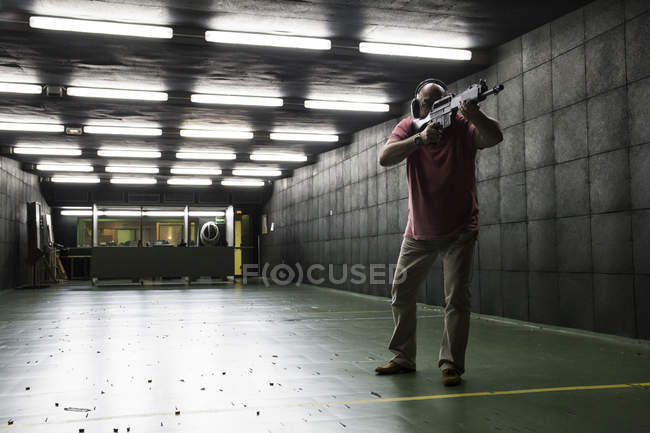 Mann zielt mit taktischer Waffe auf Indoor-Schießstand — Stockfoto