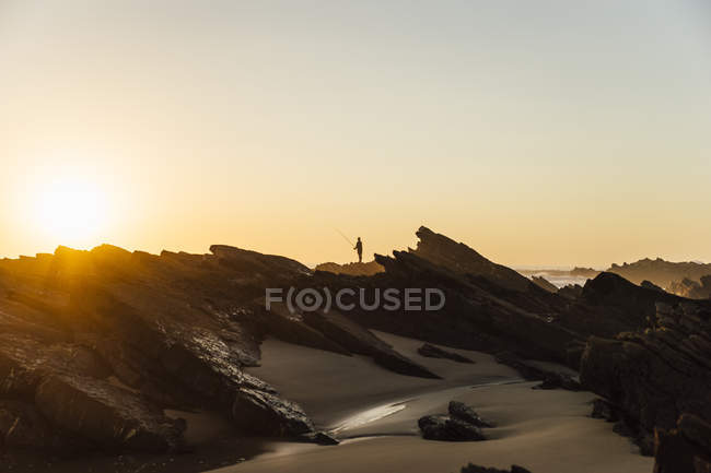 Portugal, Alentejo, silhouette of man fising at Zambujeira do Mar beach at sunset — Stock Photo