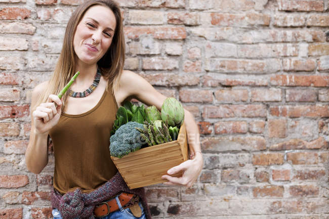 Улыбающаяся женщина держит корзину со свежими овощами — стоковое фото