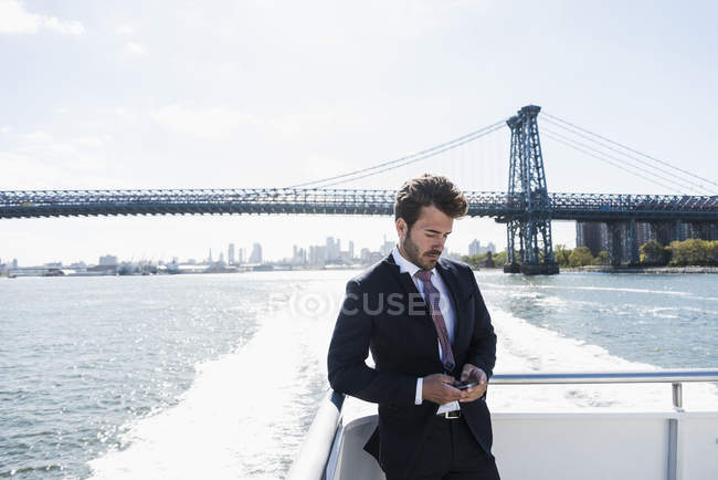 Uomo d'affari che controlla il cellulare sul traghetto a East River, New York, USA — Foto stock