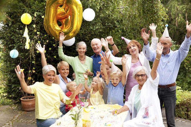 Расширенная семья и друзья празднуют день рождения в саду — стоковое фото