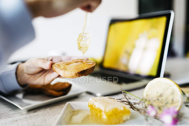Жінка кидає мед на тост на своєму робочому місці, крупним планом — стокове фото