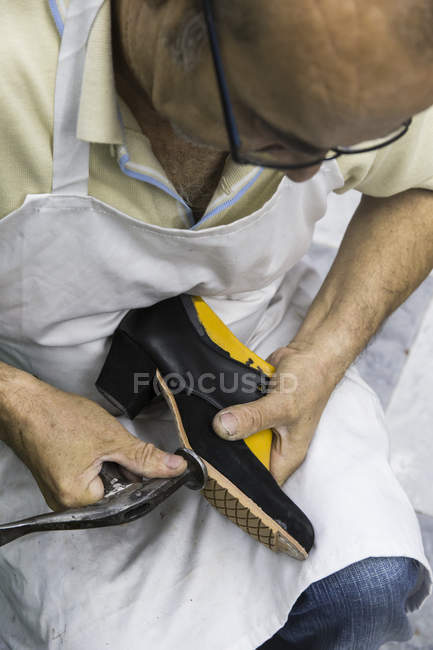 Calzolaio che lavora con martello sulla scarpa nel suo laboratorio — Foto stock
