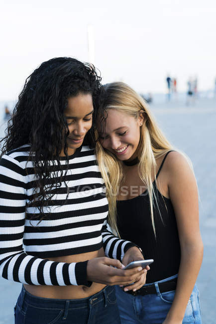 Due giovani donne che utilizzano il telefono cellulare all'aperto — Foto stock