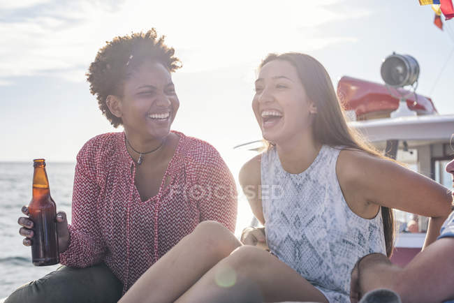 Happy friends on a boat trip having a beer — Stock Photo