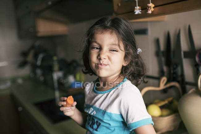 Portrait Of Little Girl Pulling Funny Face While Eating A Carrot