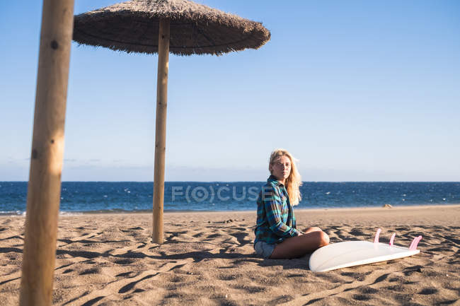 Spagna, Tenerife, giovane surfista biondo seduto sulla spiaggia di sabbia — Foto stock