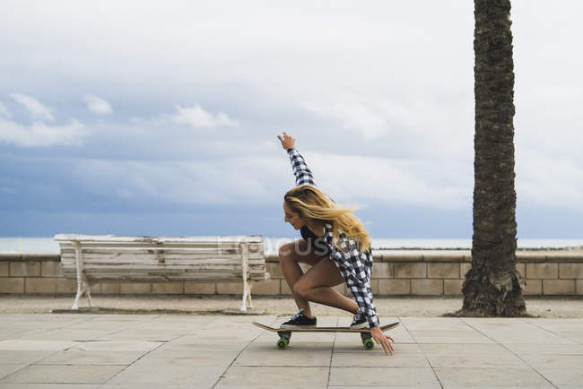 Jovem mulher equilibrando no skate no passeio marítimo — Fotografia de Stock