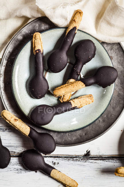 Spoon-shaped biscuits with chocolate icing on plate — Stock Photo