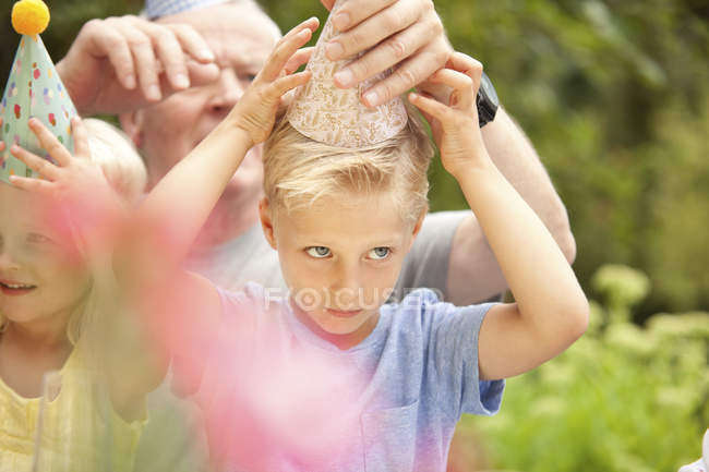 Boy putting on party hat at garden — Stock Photo