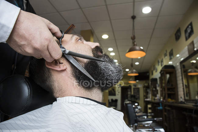 Barbeiro barba homem corte no salão de barbearia — Fotografia de Stock
