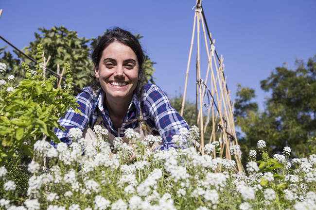 Mulher feliz trabalhando na fazenda, examinando flores — Fotografia de Stock