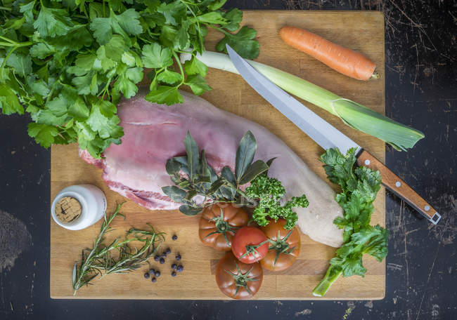 Raw cow tongue on chopping board, parsley, juniper, laurel — Stock Photo