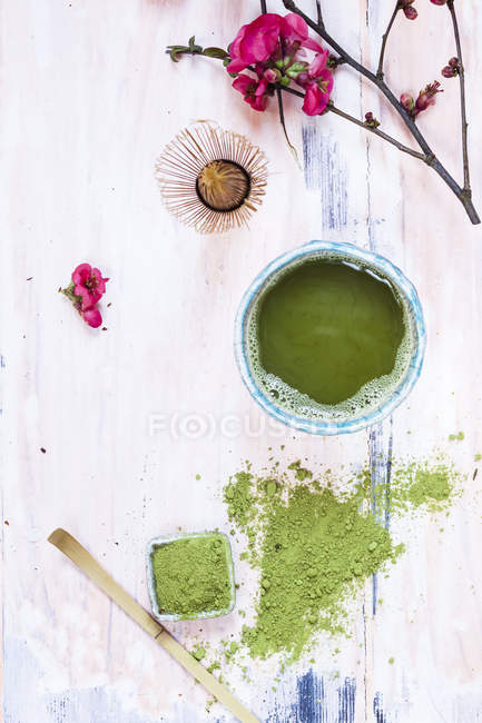 Matcha chá na tigela, com pó, colher, chasen e flores rosa — Fotografia de Stock