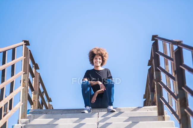 Retrato de una mujer sonriente sentada en las escaleras - foto de stock