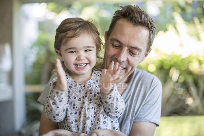 Маленька дівчинка і її батько плескаючи руках портрет — стокове фото