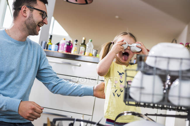 Playful Daughter And Father Clearing Dishwasher Stock Photo Playful Daughter And Father Clearing Dishwasher Stock Photo