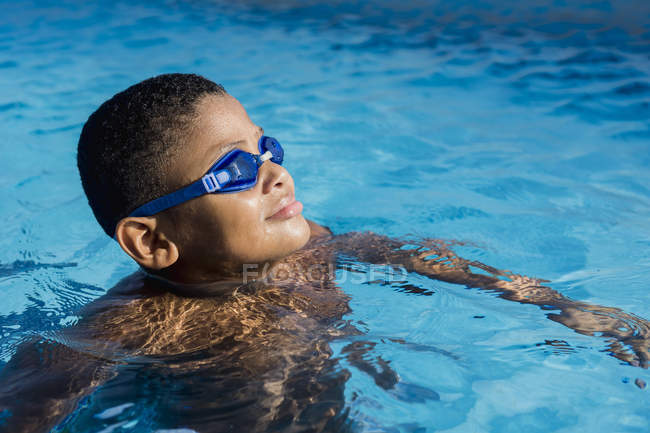 Menino na piscina em óculos de natação olhando para o lado — Fotografia de Stock