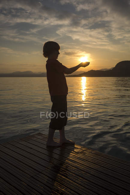 Junge hält Händchen gegen die Sonne, bei Sonnenuntergang — Stockfoto