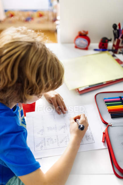 Retrato del chico pensativo haciendo la tarea en casa - foto de stock
